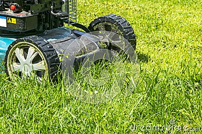 Mowing lawns, Lawn mower on green grass, mower grass equipment, mowing gardener care work tool, close up view, sunny day Stock Photo