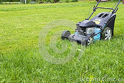 Mowing lawns. Lawn mower on green grass. mower grass equipment. mowing gardener care work tool close up view sunny day Stock Photo