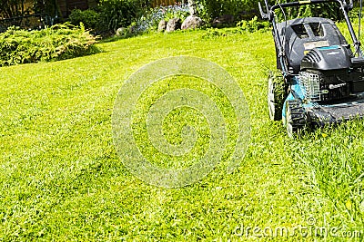 Mowing lawns, Lawn mower on green grass, mower grass equipment, mowing gardener care work tool, close up view, sunny day. Stock Photo