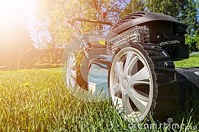 Mowing lawns, Lawn mower on green grass, mower grass equipment, mowing gardener care work tool, close up view, sunny day. Soft lig Stock Photo
