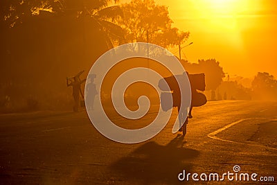 A Mozambican cyclist carrying large bags of coal to market at sunrise Stock Photo