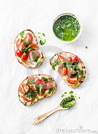 Mozzarella cheese, cherry tomatoes and arugula pesto bruschetta on light background, top view. Arugula pesto and sandwiches - tast Stock Photo