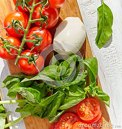 Mozzarella, organic cherry tomatoes and fresh basil on a rustic wooden background Stock Photo