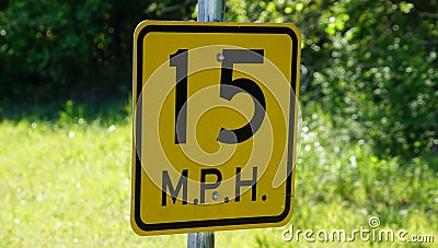 A 15 MPH sign on a country road for a sharp corner. Stock Photo