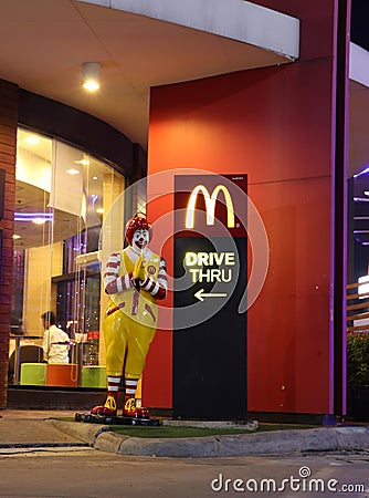 A Ronald McDonald statue, mascot standing in front of the McDonald`s drive THRU, greeting guests with the traditional Thai wai Editorial Stock Photo