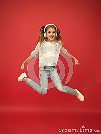 So much fun. Girl listening music modern gadget. Kid happy with wireless headset dancing jumping. Stereo headphones. Kid Stock Photo