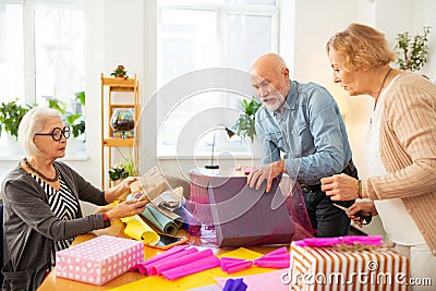 Friendly aged people being busy with gift packing Stock Photo