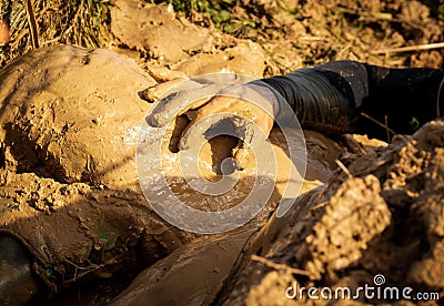 Muddy obstacle race runner in action. Mud run. Details of the hands Stock Photo