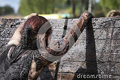 Muddy obstacle race runner in action. Mud run Editorial Stock Photo