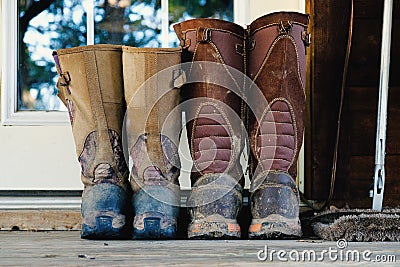 Muddy snake hunting boots on doorstep. Stock Photo