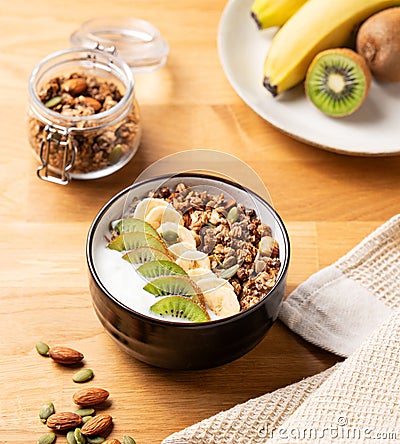 Muesli with yogurt, banana and kiwi on a wooden table Stock Photo