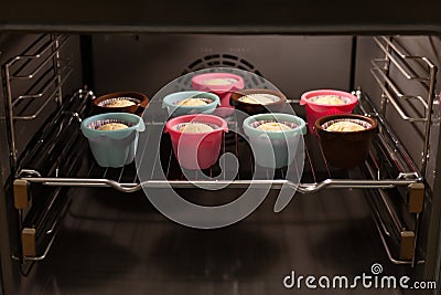 Muffins in ccolorful silicone molds growing up in the oven. Cupcakes, bakery. Close up Stock Photo