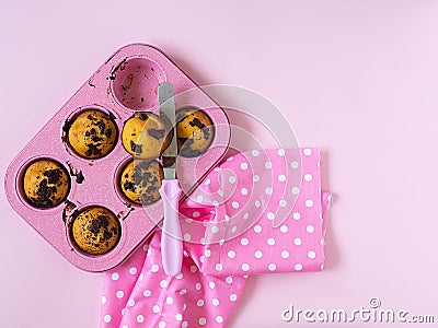 Muffins in pink cupcake shape, kitchen spatula with pink handle, pink towel with white polka dots on pink background. Stock Photo