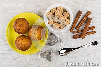 Muffins on saucer, teabags, sugar, cinnamon, teaspoon on table Stock Photo