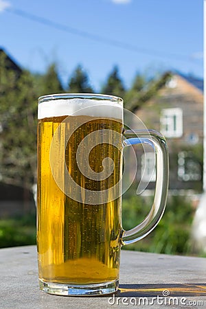 Mug of beer with foam on background of nature. Stay with alcohol on the outdoors. Stock Photo