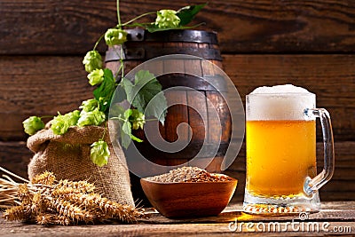 Mug of beer with green hops, wheat ears and wooden barrel Stock Photo