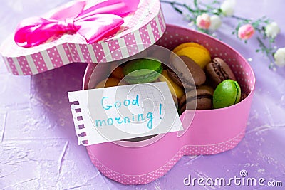 Mug cakes Macaron, leaf notebook inscription good morning on purple table top. The cozy breakfast. Stock Photo