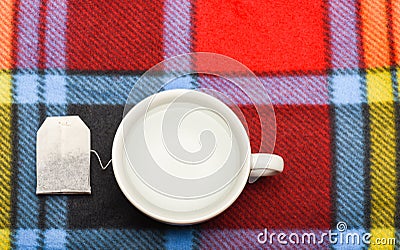 Mug filled with boiling water and teabag on colorful plaid background. Tea time concept. Process of tea brewing in Stock Photo