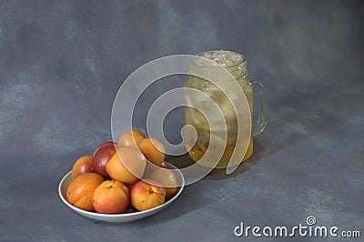 A mug of juice with ice and a plate with apricots and peaches Stock Photo