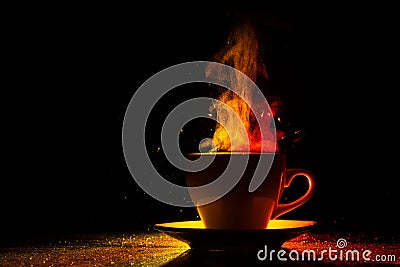 A mug with a warm drink and curly steam rising up, illuminated in red-yellow, orange on a black background Stock Photo