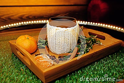 A mug of warm tea with pieces of manadarines on a wooden tray Stock Photo