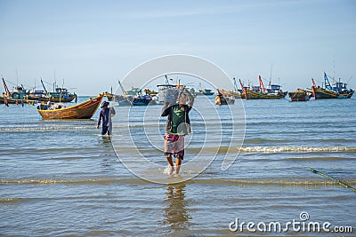 Vietnamese fisherman carries a catch from a boat to the shore Editorial Stock Photo