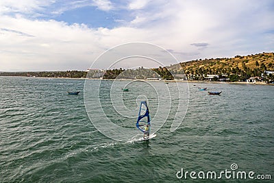 Mui Ne, Vietnam. Man play wind surfing sport in sea under vast blue sky Stock Photo