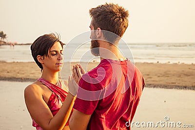 Muladhara swadhisthana manipula tantra yoga on the beach man and woman meditates sitting on the sand by the sea at Stock Photo