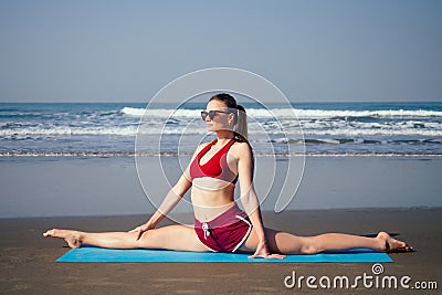 Muladhara swadhisthana manipula tantra yoga on the beach woman meditates sitting on the sand yoga mat by the sea at Stock Photo
