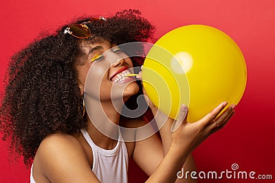 Mulatto model inflates a yellow balloon Stock Photo