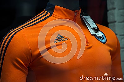 Orange teeshirt of soccer by adidas brand in a fashion store showroom Editorial Stock Photo