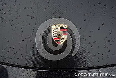 Closeup of rain drops on porsche logo on a black car parked in the street Editorial Stock Photo