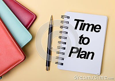 Multi-colored diaries lie on a beige background next to a pen and a notebook with the words TIME TO PLAN. Flat lay Stock Photo