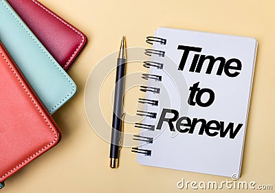 Multi-colored diaries lie on a beige background next to a pen and a notebook with the words TIME TO RENEW. Flat lay Stock Photo