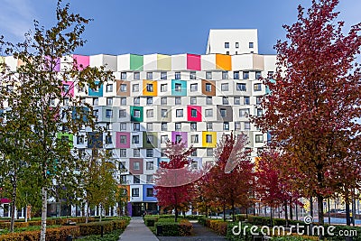 A multi-colored high-rise apartment building with a landscaped yard. Autumn colors of bushes and trees Stock Photo