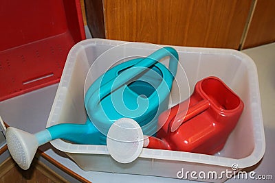 Multi-colored plastic red blue watering cans with a handle for watering plants, flowers Stock Photo