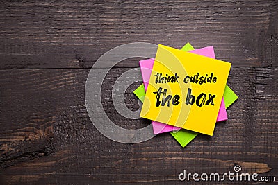 Multi-colored stickers with Think Outside The Box message on wooden background Stock Photo