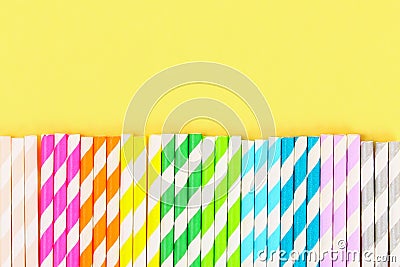 Multi-colored straw paper tubes on a bright yellow pastel background. Top view, copy space. Stock Photo