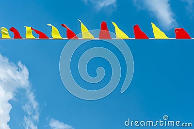 Multi colored triangular flags develop on the background of blue sky. Colorful fairground flags Stock Photo