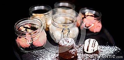 Multi-coloured marshmallows in several five cans on a black background Stock Photo