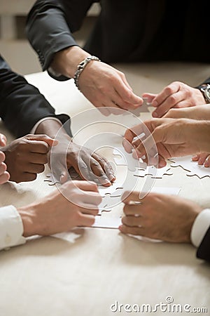 Multi-ethnic business team assembling jigsaw puzzle together, ve Stock Photo