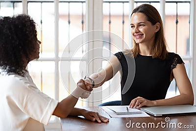 Multiethnic businesswomen greeting each other shaking hands starting business negotiations Stock Photo