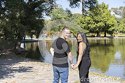 Multi-ethnic couple formed by an Andean woman and a Caucasian man walking by a lake Stock Photo