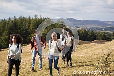 Multi ethnic group of five happy young adult friends talking as they walk on a rural path during a mountain hike Stock Photo