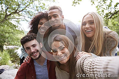 Multi ethnic group of five young adult friends pose to camera while taking a selfie during a break in a hike Stock Photo