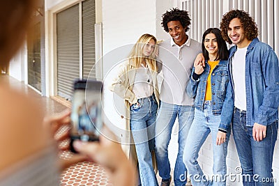 Multi-ethnic group of friends taking photos with a smartphone in the street. Stock Photo