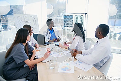 Multi-ethnic group of professional doctors discussing x-ray prints of patient in the meeting room at modern hospital Stock Photo