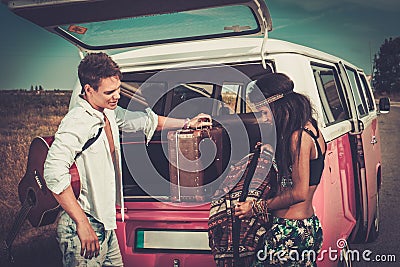 Multi-ethnic hippie couple with guitar packing luggage for a road trip Stock Photo