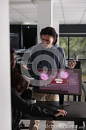 Multi ethnic team of it programmers having hacked server and security breach alert on pc Stock Photo
