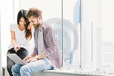 Multi-ethnic young couple or college student using notebook laptop together in campus or office. Information technology concept Stock Photo